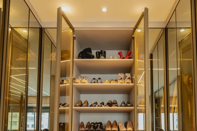 Closet de sapatos com portas de vidro e prateleiras iluminadas
