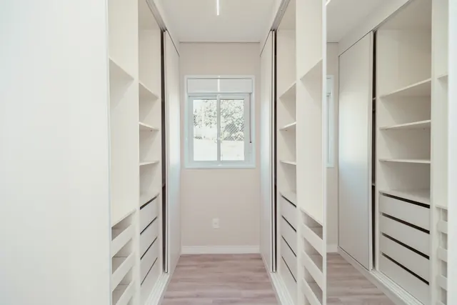Closet em corredor com prateleiras e gavetas brancas