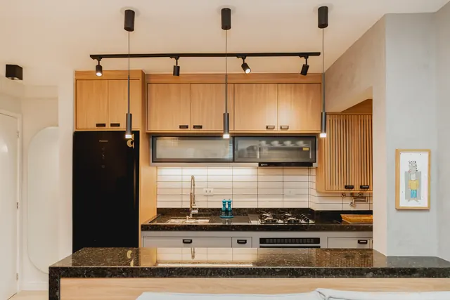 Cozinha em madeira clara com trilho de luz e bancada escura