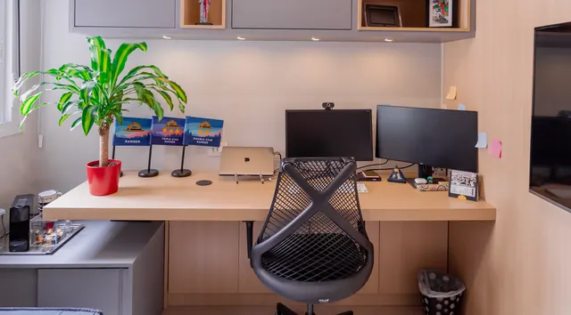Home office com bancada em madeira, armários e nichos